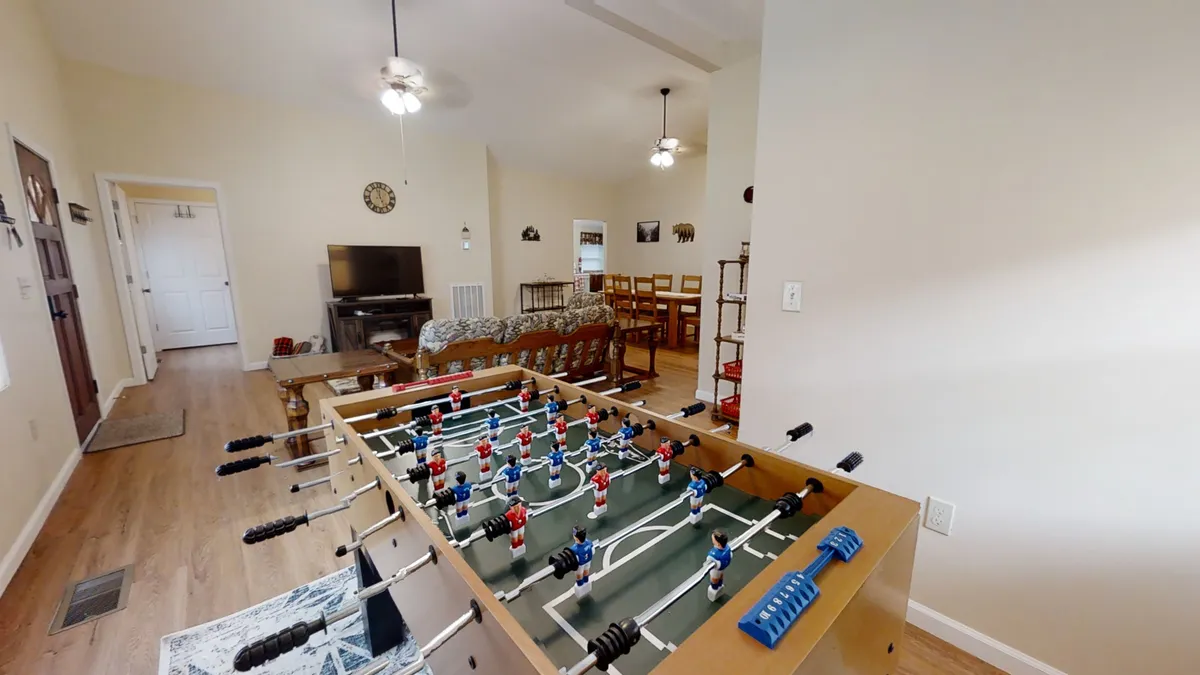 A bright, inviting interior space with a foosball table positioned near a dining area and living room seating. The scene is lively, playful, and perfect for group entertainment, reflecting opportunities for friendly competition and casual gatherings.